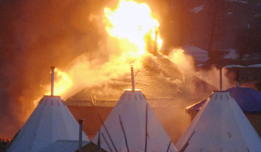A fire on a building at a camp that has been home to demonstrators against the Dakota Access pipeline is seen after protesters set fire in Cannon Ball, N.D., in the early morning of Wednesday, Feb. 22, 2017. Most of the pipeline opponents abandoned their protest camp Wednesday ahead of a government deadline to get off the federal land, and authorities moved to arrest some who defied the order in a final show of dissent. Earlier in the day, some of the last remnants of the camp went up in flames when occupants set fire to makeshift wooden housing as part of a leaving ceremony. (Mike Mccleary/The Bismarck Tribune via AP)
