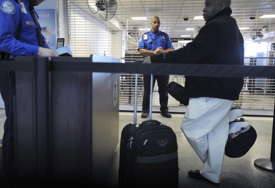In this Jan. 6, 2010, file photo, a TSA employee being trained in behavioral pattern recognition watches passengers in line at a security checkpoint at Logan International Airport in Boston. (AP Photo/Josh Reynolds, File)