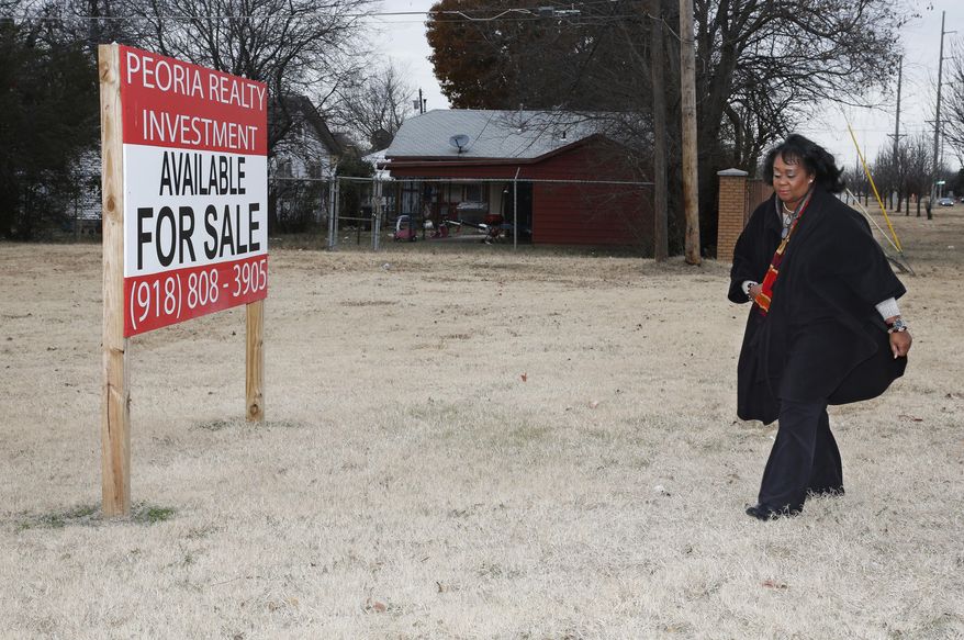 In this Thursday, Dec. 15, 2016 photo, Donna Jackson, NorthTulsa100 executive director, walks through a vacant lot for sale in north Tulsa, Okla. A once-prosperous section of Tulsa that became the site of one of the worst race riots in American history is attempting to remake itself again after decades of neglect. Black leaders want to bring 100 new companies to the former Black Wall Street in north Tulsa by 2021, the 100th anniversary of its fall. (AP Photo/Sue Ogrocki)