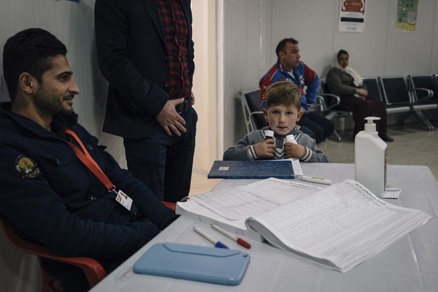 In this Jan. 12, 2017 photo, a boy holds two small bottles of medicine at a clinic inside the Sharya camp for civilians displaced by war in Iraq. A new psychological trauma institute is being established at the university of Dohuk in Iraq, the first in the entire region. The program will train local mental health professionals to treat Islamic State victims, including thousands of Yazidi women and children. It will open at the end of the month. (AP Photo/Alice Martins)