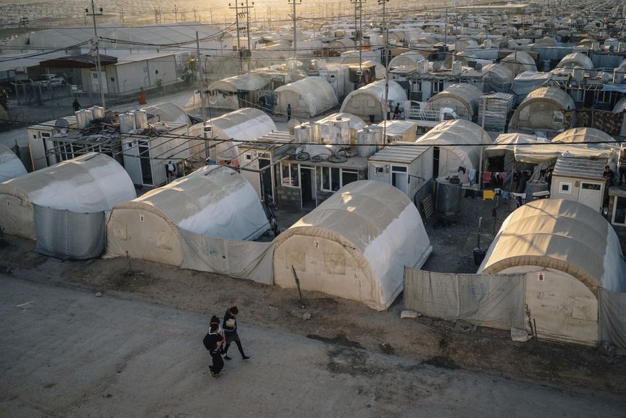 In this Jan. 11, 2017 photo, Yazidi children walk carrying school books at the Kabarto camp for civilians displaced by war in Iraq. A new psychological trauma institute is being established at the university of Dohuk in Iraq, the first in the entire region. The program will train local mental health professionals to treat Islamic State victims, including thousands of Yazidi women and children. It will open at the end of the month. (AP Photo/Alice Martins)