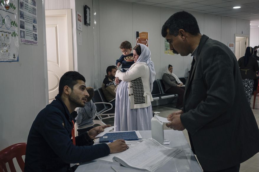 In this Jan. 12, 2017 photo, a Yazidi woman holds a child at a clinic inside the Sharya camp for civilians displaced by war in Iraq. A new psychological trauma institute is being established at the university of Dohuk in Iraq, the first in the entire region. The program will train local mental health professionals to treat Islamic State victims, including thousands of Yazidi women and children. It will open at the end of the month. (AP Photo/Alice Martins)