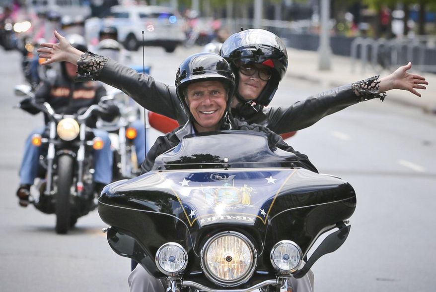 FILE - In this June 27, 2016, New York Gov. Andrew Cuomo and his girlfriend Sandra Lee ride in a breast cancer awareness motorcycle event in New York. Following Lee's successful battle with breast cancer Gov. Cuomo called for big investments to fight cancer last year, but now seeks to cut $25 million from public health programs that pay to fight cancer, diabetes and other conditions. (AP Photo/Seth Wenig, File)