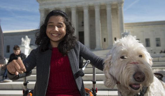 FILE - In this Oct. 31, 2016 file photo, Ehlena Fry of Michigan, sits with her service dog Wonder, while speaking to reporters outside the Supreme Court in Washington. The Supreme Court says a lower court should take another look at whether Fry, who has cerebral palsy can sue Michigan school officials over their refusal to let her to bring a service dog to class.  (AP Photo/Molly Riley, File)