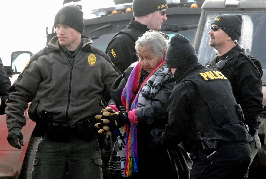 An elderly woman is escorted to a transport van after being arrested by law enforcement at the Oceti Sakowin camp as part of the final sweep of the Dakota Access pipeline protesters on Thursday in Morton County near Cannon Ball, North Dakota. (Associated Press photographs)