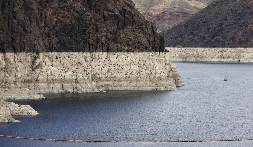 FILE – In this April 16, 2013 file photo, a "bathtub ring" marks the high water mark as a recreational boat approaches Hoover Dam along Black Canyon on Lake Mead, the largest Colorado River reservoir, near Boulder City, Nev. Scientists say global warming may already be shrinking the Colorado River and could reduce its flow by more than a third by the end of the century. (AP Photo/Julie Jacobson, File)
