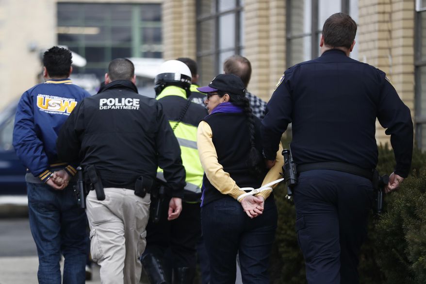 People are taken into custody by Elizabeth Police officers during an immigration protest outside of a detention center, Thursday, Feb. 23, 2017, in Elizabeth, N.J. More than 100 protesters lined the street outside of the detention center. They chanted against recent raids by federal immigration authorities and against President Donald Trump's proposed wall on the Mexican border. (AP Photo/Julio Cortez)