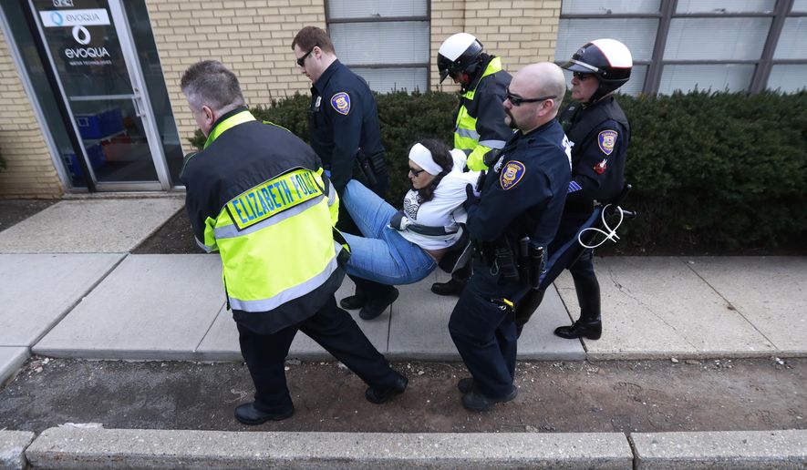Diana Mejia, center, an activist with Winds of the Spirit N.J., is carried by Elizabeth Police officers while being arrested during an immigration protest outside of a detention center, Thursday, Feb. 23, 2017, in Elizabeth, N.J. Mejia and four other activists were taken into custody during the rally. (AP Photo/Julio Cortez)