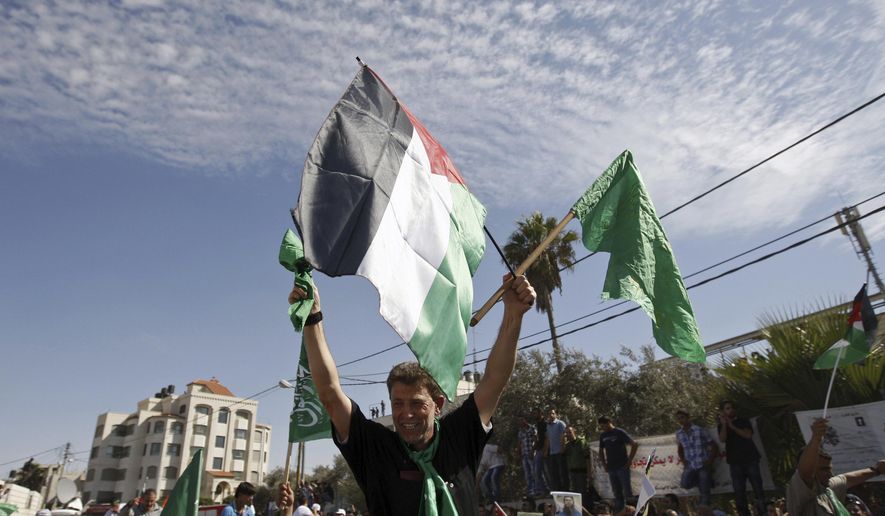 File - In this Tuesday, Oct. 18, 2011 file photo, Hamas militant Nael Barghouti waves a green Islamic flag and a Palestinian flag to the crowd after arriving in the West Bank city of Ramallah. after he was released in exchange of an Israeli soldier held by Hamas. Hundreds of other Palestinian prisoners were also released in this exchange. A Palestinian activist says an Israeli court ordered Barghouti to complete his life sentence, At the time of the exchange, Nael Barghouti had served 33 years for participating in the kidnapping and killing of an Israeli soldier, making him one of the longest-held Palestinians. (AP Photo/Majdi Mohammed, File)