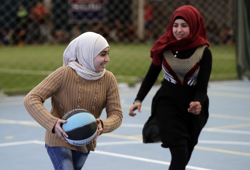 In this picture taken on Sunday, Feb. 19, 2017, Syrian refugee girls play a basketball game at a private sports club, southern Beirut, Lebanon. Every Sunday the gymnasium in Beirut echoes with the shouting and laughter of dozens of children, mostly Syrian refugees enjoying a rare escape from a grim and cloistered life in exile. The Sport 4 Development program, run by the U.N. children's agency, aims to bring 12,000 children, mostly Syrian refugees, to blacktops and turf pitches this year to teach the basics of soccer and basketball, and to ease the pain of war and displacement. (AP Photo/Hussein Malla)