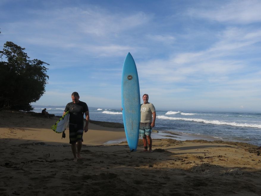 In this Feb. 16, 2017 photo, surfers Doug Lake, left, and Danny King pose for a picture at Wilderness Beach, in Aguadilla, a lush corner in northwest Puerto Rico that has remained largely untouched since Christopher Columbus landed there in his second voyage to the New World. The area could soon become the site of a $200 million development that is pitting environmentalists who seek to convert the land into a national park against those who say the Christopher Columbus Landing resort could create jobs, generate tourism and boost real estate prices amid an economic crisis. (AP Photo/Danica Coto)