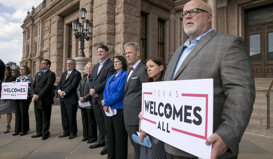 FILE - In this Jan. 11, 2017, file photo, Brad Kent, chief sales and services officer for Visit Dallas, holds a sign at a news conference at the state capitol in Austin, Texas, to oppose a Texas "bathroom bill." Bills to curtail transgender people's access to public restrooms are pending in a dozen states, but even in conservative bastions such as Texas and Arkansas they may be doomed by high-powered opposition. (Jay Janner/Austin American-Statesman via AP, File)
