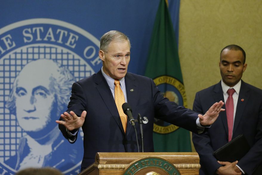 Washington Gov. Jay Inslee, left, talks to reporters, as general counsel Nick Brown looks on at right, Thursday, Feb. 23, 2017, at the Capitol in Olympia, Wash., after Inslee signed an executive order Thursday to ensure that state workers don't help carry out President Donald Trump's immigration policies. Trump has said he wants to expand the number of deportations of people in the country illegally, and Inslee said Thursday that his order reaffirms the state's commitment to tolerance and ensures that state workers roles are to provide services for residents and not to enforce immigration statutes. (AP Photo/Ted S. Warren)