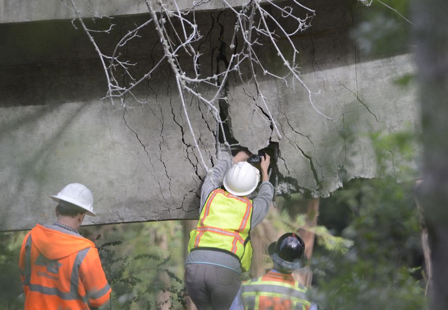 In this Wednesday, Feb. 22, 2017 photo, a Caltrans engineer shoots a photo of the inside of a large crack on the Pfeiffer Canyon Bridge on Highway 1 in Big Sur, Calif. On the rain-soaked coast in Central California, the Pfeiffer Canyon Bridge has crumble beyond repair, blocking passage on the north-south Highway 1 route for up to a year. Until it is rebuilt, visitors can drive up to view the roughed coastline, then turn back. (David Royal /The Monterey County Herald via AP)