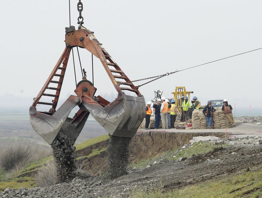 FILE - In this Feb. 15, 2017, file photo, a load of rocks is dropped to patch a crater as repairs are made on the Tyler Island levee near Isleton, Calif. Billions of dollars of flood projects in the past two decades have eased fears of levee breaks in Sacramento and other Central Valley cities. But flood experts say levees protecting farms and farm towns also need billions of dollars in maintenance and upgrades. (AP Photo/Rich Pedroncelli, file)