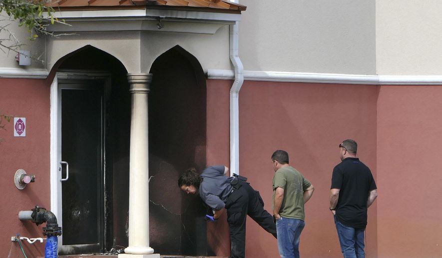 Fire officials inspect a side door where an arson took place at the Daarus Salaam Mosque in Thonotosassa, Fla., Friday, Feb. 24, 2017. (James Borchuck/The Tampa Bay Times via AP)