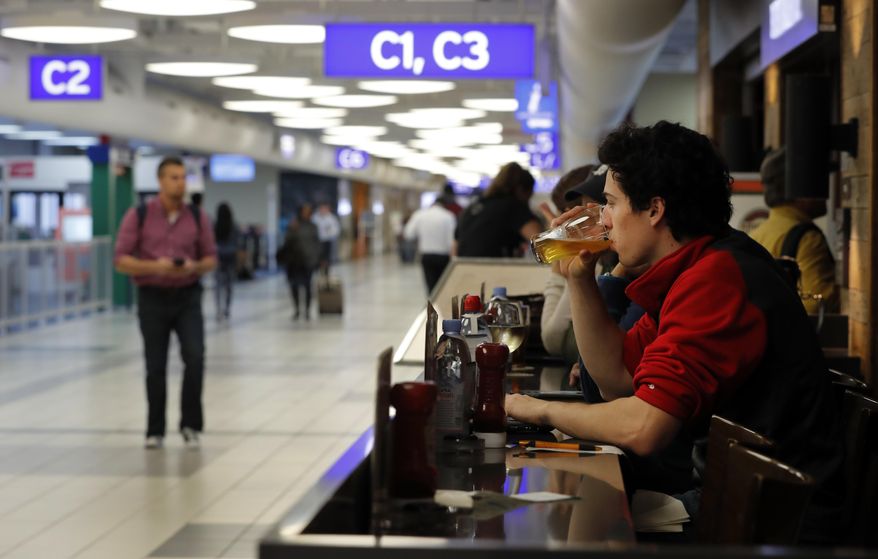 In this photo made Friday, Feb. 24, 2017, traveler Dominic Maley sips on a beer while waiting to board a flight at St. Louis Lambert International Airport in St. Louis. The Missouri House has passed a proposal that would allow people to bring alcohol out of airport bars and restaurants to gates. (AP Photo/Jeff Roberson)