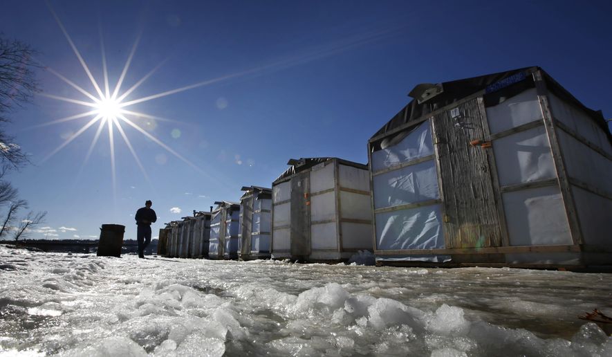 FILE - In this Jan. 10, 2013 file photo, fisherman Tom Cowper of Peabody, Mass., walks from his ice fishing shack at Jim Worthing's Smelt Camp on the Kennebec, River in Pittston, Maine. Fishermen and state regulators said the population of smelt appears to have made a comeback in 2017 after a down year in which few of them were caught. Ice fishing for smelts is a winter tradition in Maine, where the small fish are fried and eaten whole. (AP Photo/Robert F. Bukaty, File)
