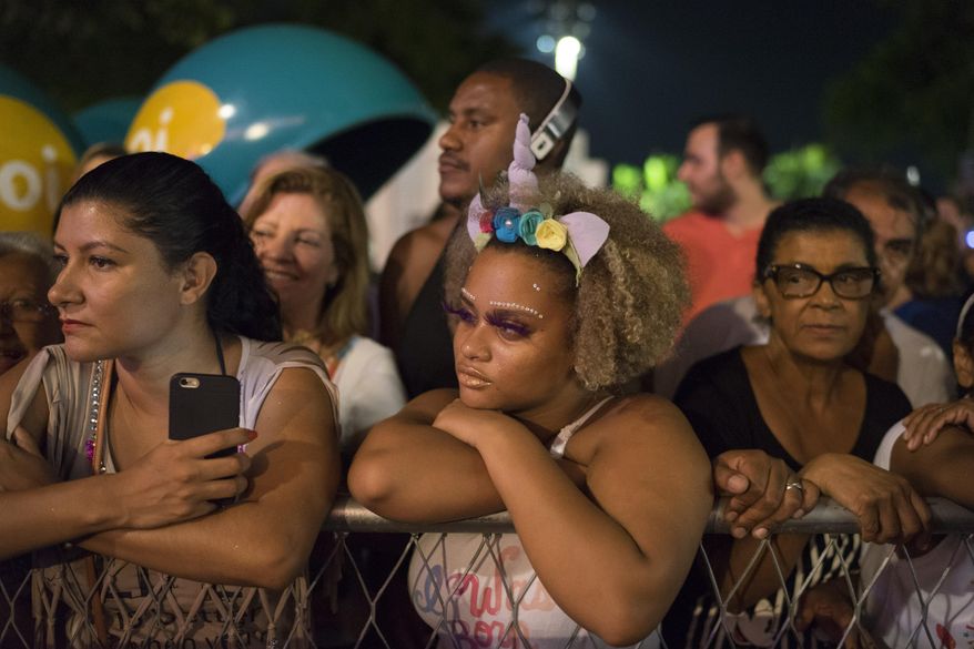 People on the sidewalk watch guests arriving to a traditional Carnival ball at the Copacabana Palace hotel in Rio de Janeiro, Brazil, Saturday, Feb. 25, 2017. In stark contrast to the hundreds of hard-charging street parties across Rio that are open to anyone, the "Baile do Copa" bills itself as a fairytale event where the country's elite can see and be seen in a hotel known for both opulence and a lengthy tradition of welcoming world leaders and stars. (AP Photo/Leo Correa)