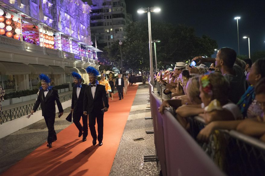 Guests walk on the red carpet as they arrive to a traditional Carnival ball at the Copacabana Palace hotel in Rio de Janeiro, Brazil, Saturday, Feb. 25, 2017. In stark contrast to the hundreds of hard-charging street parties across Rio that are open to anyone, the "Baile do Copa" bills itself as a fairytale event where the country's elite can see and be seen in a hotel known for both opulence and a lengthy tradition of welcoming world leaders and stars. (AP Photo/Leo Correa)