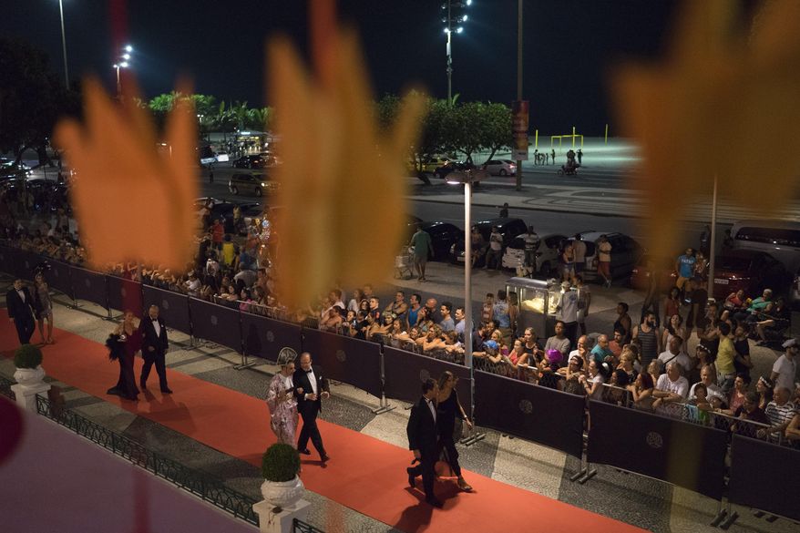 Guests walk on the red carpet as they arrive to a traditional Carnival ball at the Copacabana Palace hotel in Rio de Janeiro, Brazil, Saturday, Feb. 25, 2017. In stark contrast to the hundreds of hard-charging street parties across Rio that are open to anyone, the "Baile do Copa" bills itself as a fairytale event where the country's elite can see and be seen in a hotel known for both opulence and a lengthy tradition of welcoming world leaders and stars. (AP Photo/Leo Correa)