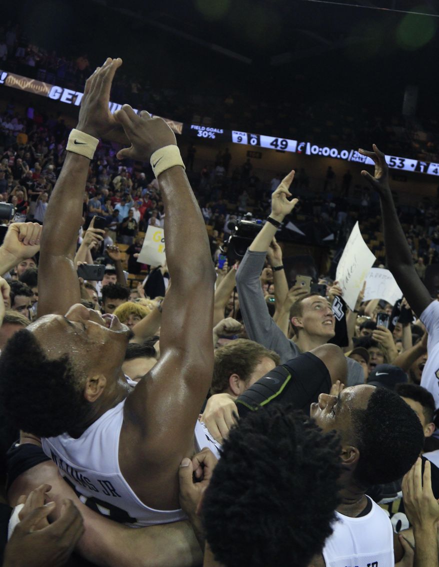 Central Florida guard Matt Williams, center, is lifted by players and students at center court after defeating Cincinnati 53-49 during an NCAA college basketball game in Orlando, Fla., on Sunday, Feb. 26, 2017. (AP Photo/Reinhold Matay)