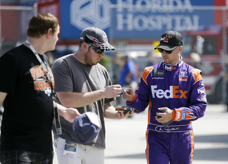 Denny Hamlin, right, signs autographs for fans as he walks to his garage at a NASCAR auto racing practice session at Daytona International Speedway, Friday, Feb. 24, 2017, in Daytona Beach, Fla. (AP Photo/John Raoux)