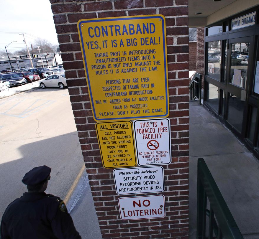 In this Tuesday, Feb. 21, 2017 photo, corrections officer passes a contraband warning sign outside the visitor's entrance at the New Hampshire State Prison in Concord, N.H. The banning of vending machines, greeting cards and recently kissing by inmate visitors at the prison has forced an effort to stop the flow of drugs into the prison. (AP Photo/Charles Krupa)