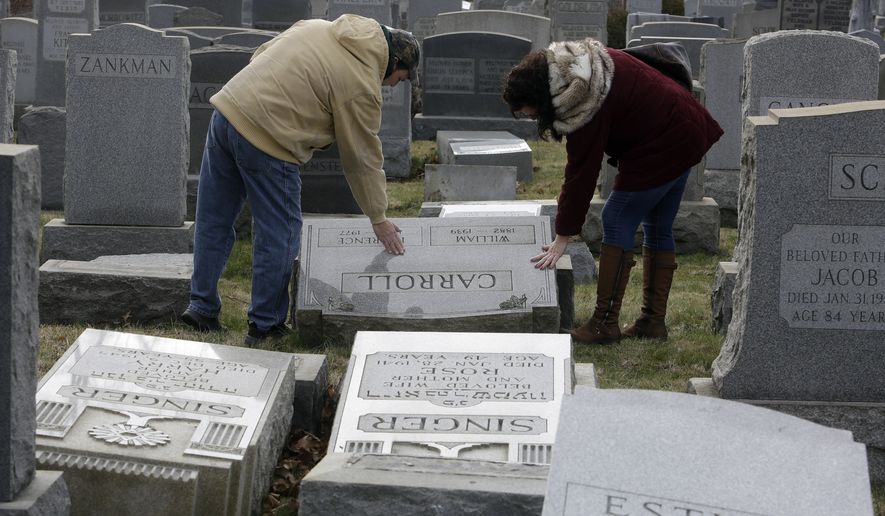 Joe Nicoletti and Ronni Newton of the Taconey Holmesburg town watch group pay their respects at a damaged headstone in Mount Carmel cemetery Monday, Feb. 27, 2017, in Philadelphia. More than 100 headstones have been vandalized at the Jewish cemetery in Philadelphia, damage discovered less than a week after similar vandalism in Missouri, authorities said.(AP Photo/Jacqueline Larma)