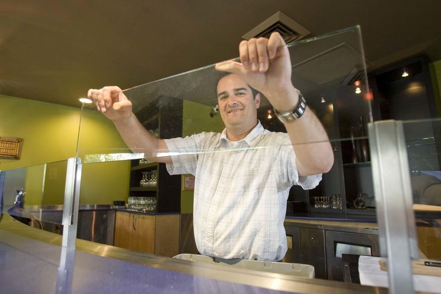 In this 2009 photo, Shawn Boyle, general manager of Faustina restaurant in Salt Lake City, demonstrates how easily the "Zion Curtain" barrier can be removed from the restaurant's bar area. In heavily Mormon Utah, a lawmaker introduced a proposal Monday, Feb. 27, 2017, that allows restaurants to get rid of barriers that block people from seeing alcoholic drinks being made, a shield that supporters curbs underage drinking by hiding the glamour of bartending. (Paul Fraughton/The Salt Lake Tribune via AP)