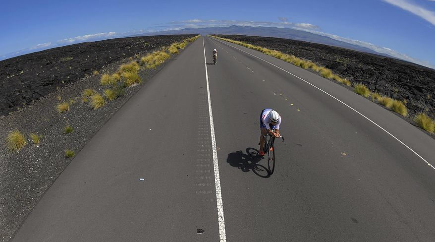 FILE - In this Oct. 8, 2016, file photo, a competitor rides through the lava fields during the cycling portion of the Ironman World Championship Triathlon in Kailua-Kona, Hawaii. The photo was part of a series of images by photographer Mark J. Terrill which won the Thomas V. diLustro best portfolio award for 2016 given out by the Associated Press Sports Editors during their annual winter meeting in Lake Buena Vista, Fla. (AP Photo/Mark J. Terrill, File)