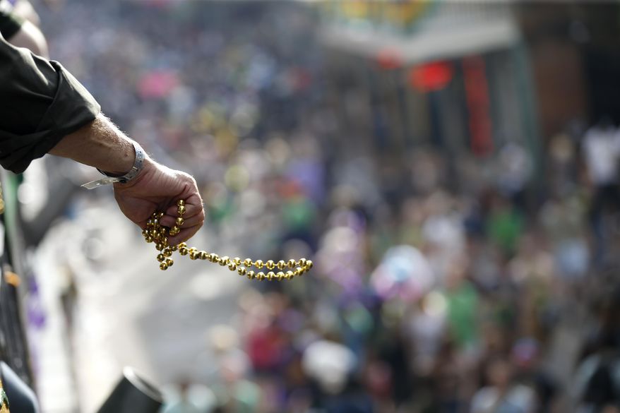 Revelers toss beads from the balcony of the Royal Sonesta Hotel on Bourbon Street Mardi Gras day in New Orleans, Tuesday, Feb. 28, 2017. (AP Photo/Gerald Herbert)