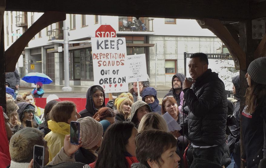 In this Monday, Feb. 27, 2017, photo, protesters gather during a rally outside an Immigration and Customs Enforcement office in Portland, Ore. Federal immigration officers stopped two vans carrying 19 workers headed to a forest in Oregon to pick an ornamental shrub and took 10 of them away, an activist said Tuesday. (AP Photo/Andrew Selsky)
