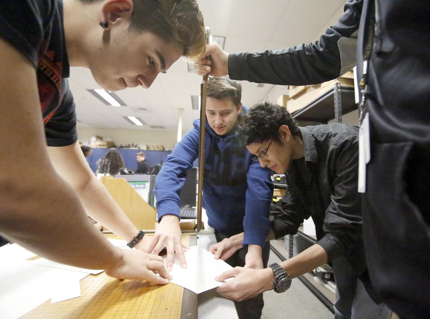 In this Jan. 20, 2017 photo, Streamwood High School students start to cut their initial design of a micro generator using wind power to light up areas around homeless shelters, at the school in Streamwood, Ill. Their wind-powered generator idea won the state competition in the Samsung Solve for Tomorrow contest, which encourages teachers and students to solve real-world issues using classroom skills in science, technology, engineering, arts and mathematics. (Brian Hill/Daily Herald, via AP)