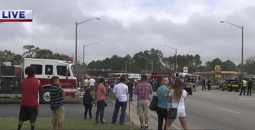 In this image made from a video provided by FOX10 News people watch as authorities respond to the scene after an SUV accelerated and hit members of a high school band at the start of a Mardi Gras parade in Gulf Shores, Ala., Tuesday, Feb. 28, 2017. (Franz Barraza/FOX10 News via AP) MANDATORY CREDIT