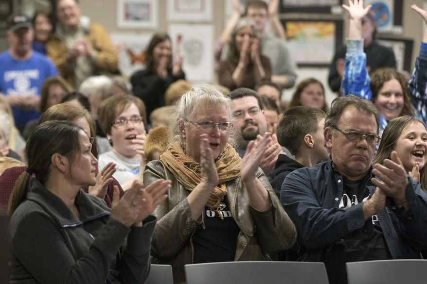 In this Tuesday, Feb. 28, 2017 photo, Michaela Fisher, center, her husband, Thomas, right, and others cheer after the Council Bluffs Community School District Board of Education voted down the district's proposal to close Crescent Elementary School during a meeting at the district's Educational Service Center in Council Bluffs, Iowa. (Joe Shearer /The Daily Nonpareil via AP)