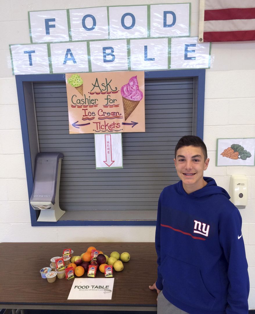 In this Tuesday, Feb. 28, 2017 photo, Nick Iannone, 14, poses in front of the share table he launched as a school project at James H. Moran Middle School in Wallingford, Conn. School officials there are criticizing a state policy change that restricts sharing of some uneaten food items. (AP Photo/Michael Melia)