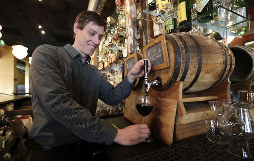 FILE - In this file photo taken Tuesday, Jan. 10, 2017, restaurant manager Jason Appleton pours a glass of wine from a small barrel at Luc's restaurant as he demonstrates that the same system could be used for consumers using their own growlers, in Seattle. The state of Washington produced a record harvest of wine grapes in 2016. The Washington Wine Commission reported Wednesday, March 1, that the 2016 harvest was 270,000 tons, up 22 percent from the previous year. (AP Photo/Elaine Thompson, File)