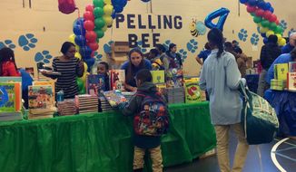KPMG employee volunteers and officials from First Book doled out free books to more than 450 children Thursday at the &quot;Read to Succeed&quot; book fair, which aims to boost childhood literacy. (Julia Brouillette/The Washington Times)