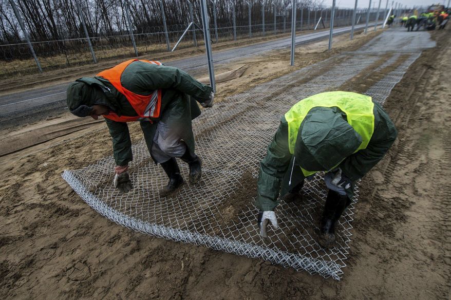 Convicts build the fence of the second defence line behind the first protective fence on the border between Hungary and Serbia near Kelebia, 178 kms southeast of Budapest, Hungary, Wednesday, March 1, 2017. The Hungarian government decided to construct a second fence along the border with Serbia to prevent migrants' illegal entry into Hungary last Thursday, Febr. 23. (Sandor Ujvari/MTI via AP)