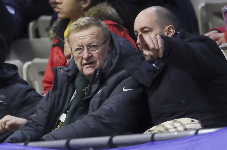 FILE - In this Feb. 20, 2017 file photo, the International Olympic Committee Vice President John Coates, left, looks at a men's 1500 meters heat of short track speed skating competition at the Asian Winter Games at Makomanai Indoor Skating Rink in Sapporo, northern Japan. Coates said the club that is set to host the 2020 Olympic golf tournament must change its policy of excluding women as full members or the event will go elsewhere. (AP Photo/Eugene Hoshiko, File)