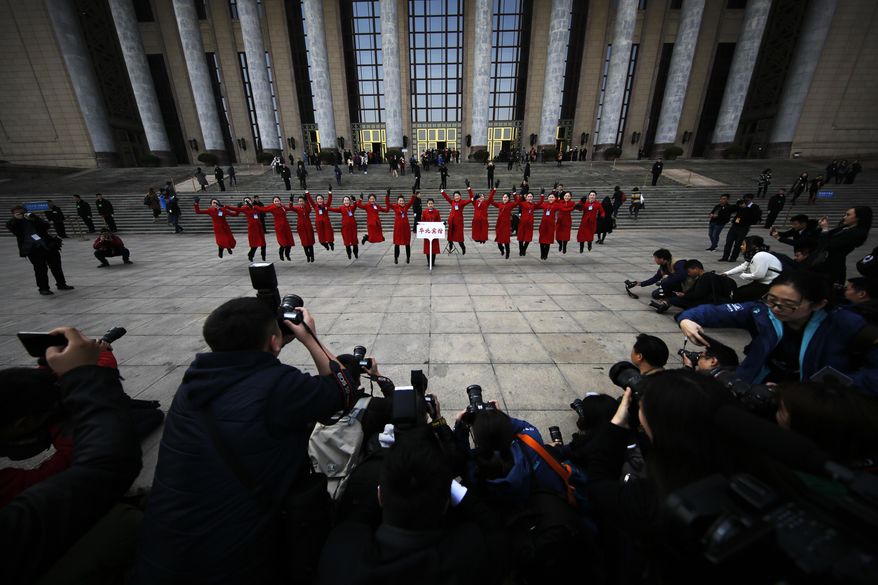 Bus ushers jump as they pose for photographs in front of the Great Hall of the People during the Chinese People's Political Consultative Conference (CPPCC) in Beijing, Friday, March 3, 2017. Thousands of delegates have gathered at the Chinese capital for the opening of the annual session of the Chinese People's Political Consultative Conference, which advises the rubberstamp parliament, whose annual session begins Sunday. (AP Photo/Andy Wong)