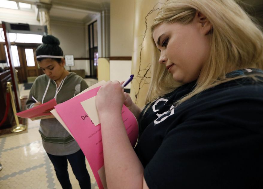 Friends Diana Hodges, left, and Macy Hudson, both of Morton, prepare a number of sticky notes calling for freeing 22-year old Daniela Vargas, a Argentine native who has lived in the United States since she was seven years old, following a brief rally on her behalf, at the Capitol in Jackson, Miss., Friday, March 3, 2017, Vargas was detained, March 1, by immigration agents who state that she is a "unlawfully present Argentinian citizen" during a "targeted immigration enforcement action." A small group of supporters placed the notes on the office doors of lawmakers in the Capitol. (AP Photo/Rogelio V. Solis)