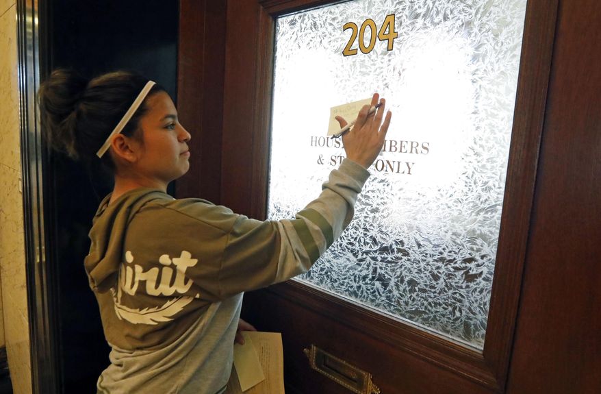 Diana Hodges places a sticky note that calls for freeing 22-year old Daniela Vargas, a Argentine native who has lived in the United States since she was seven years old, on the office doors of lawmakers at the Capitol in Jackson, Miss., Friday, March 3, 2017, Vargas was detained, March 1, by immigration agents who state that she is a "unlawfully present Argentinian citizen" during a "targeted immigration enforcement action." (AP Photo/Rogelio V. Solis)