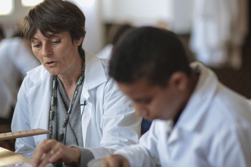 In this photo dated Tuesday, Feb. 28, 2017, a teatcher, Sandra Charteau, supervises the work of children at an informal school run by Moroccan fashion designer Fadila El Gadi, in Sale, near Rabat, Morocco. A globally successful Moroccan fashion designer returned to her hometown and founded an unusual sewing school aimed at helping poor, troubled children find a path, in a country where youth unemployment is high and the lure of extremism lurks. (AP Photo/Mosa'ab Elshamy)