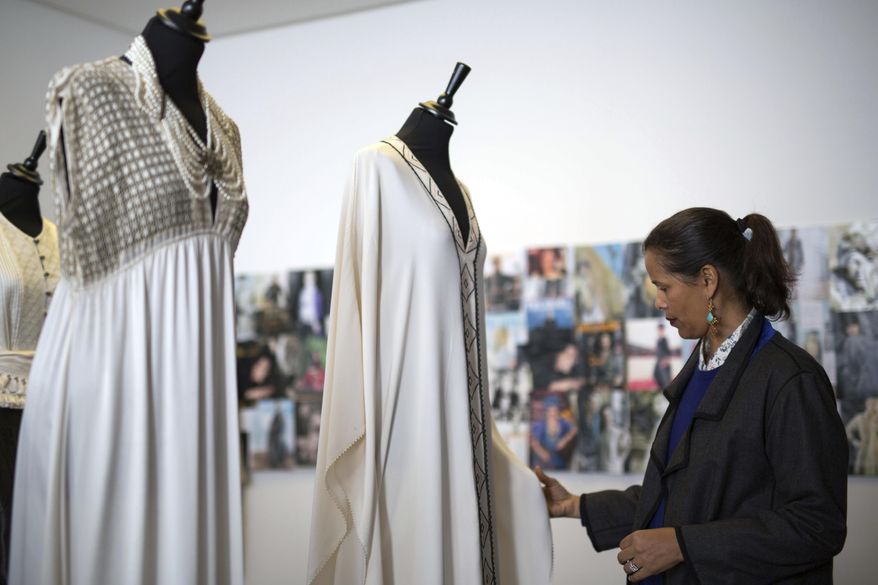 In this photo dated Tuesday, Feb. 28, 2017, Moroccan fashion designer Fadila El Gadi inspects dresses displayed in her showroom in Sale, near Rabat, Morocco. A globally successful Moroccan fashion designer returned to her hometown and founded an unusual sewing school aimed at helping poor, troubled children find a path, in a country where youth unemployment is high and the lure of extremism lurks. (AP Photo/Mosa'ab Elshamy)