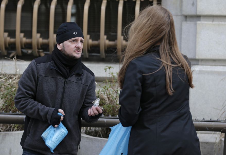Ted Farkas, 47, receives money from a passerby, Wednesday, March 1, 2017, in Cleveland. Farkas has been homeless for about five months. A lawsuit filed by the ACLU on behalf of a homeless man and a Cleveland advocacy group included the surprising number of more than 5,800 citations for panhandling issued by Cleveland police between 2007 and August 2015. (AP Photo/Tony Dejak)