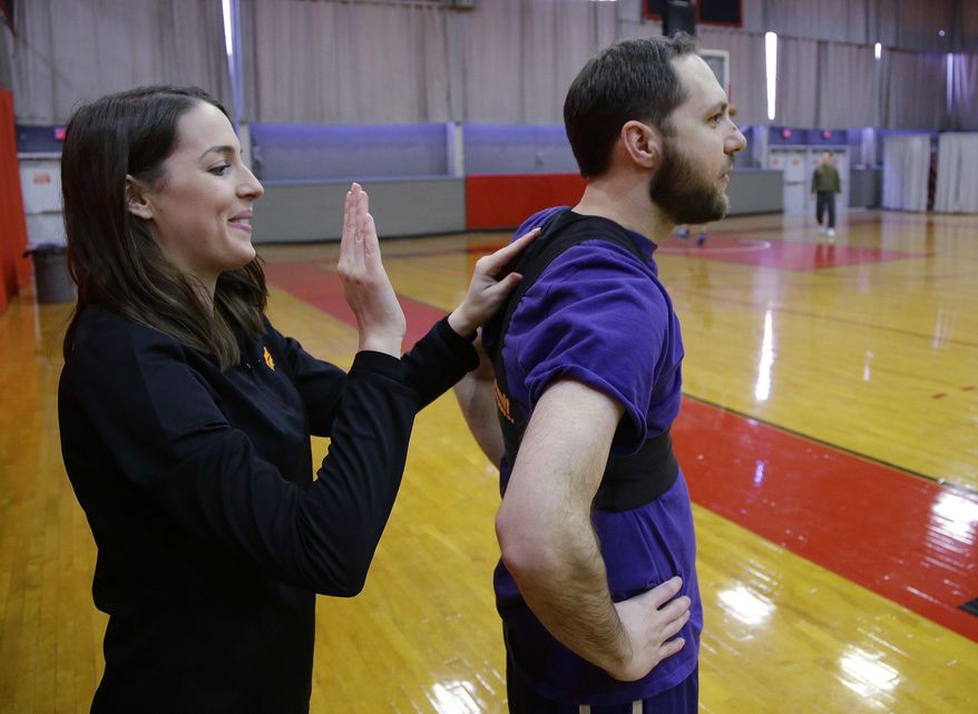 Charlotte Westover, Catapult marketing coordinator, adjusts a Catapult monitoring system compression vest on Kevin Pelton before he plays basketball Friday, March 3, 2017, in Cambridge, Mass. Athlete trackers are being used by hundreds of teams in dozens of sports helping coaches plan their practices, make substitutions in games and decide when a player is ready to return from an injury by accumulating biometric and positioning data collected from the trackers. (AP Photo/Stephan Savoia)