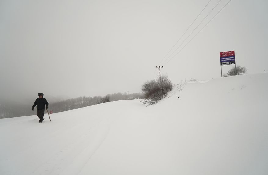 In this Thursday, Feb. 16, 2017 photo, a man walks by land offered for sale close to a construction site of developments, in Turkey Black Sea region's city of Samsun. At least four projects to lure visitors from the Gulf region and Arab nations are underway along Turkey's more traditional and conservative Black Sea coastline, where _ unlike Turkey's more popular Mediterranean and Aegean coasts _ residents and visitors opt for full body covering swimsuits and where bars selling alcohol are few and far between. (AP Photo/Neyran Elden)