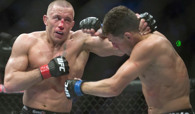 FILE - In this March 16, 2013, file photo, Georges St. Pierre, left, lands a blow to Nick Diaz, from the United States, during their UFC 158 welterweight mixed martial arts title fight in Montreal. Although St. Pierre has been out of the UFC for 3 1/2 years, the Canadian is still one of the biggest names in MMA. The longtime welterweight champ&#x27;s comeback fight later this year will be for Michael Bisping&#x27;s middleweight belt. (Graham Hughes/The Canadian Press via AP, File)